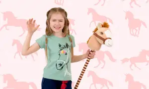Uśmiechnięta dziewczynka z konikiem na patyku, gotowa do zabawy w hobby horsing na tle różowych jednorożców.