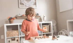 Chłopiec bawi się piaskiem i muszelkami, szukając inspiracji na 100 sposobów na nudę dla dzieci.