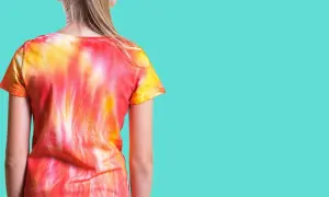 Dziewczynka w koszulce tie dye w odcieniach czerwieni i żółci. Zobacz, jak zrobić tie dye krok po kroku!