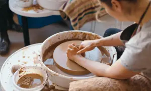 Dzieci tworzą ceramikę na kole garncarskim. Ręce formują glinę, tworząc pierwsze dzieła.
