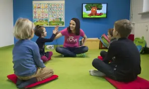 Nauczycielka z uśmiechem przybija piątkę z dziećmi. Wesoła nauka angielskiego dla 4 latka w kolorowej sali.