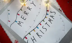 Świąteczne rysunki ołówkiem z kolorowymi lampkami tworzą napis "Merry Christmas".