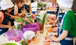 Dzieci w fartuszkach i czapkach kucharskich kroją warzywa. Wspaniałe pomysły na warsztaty dla dzieci, pełne świeżych ziół i kolorowych warzyw.