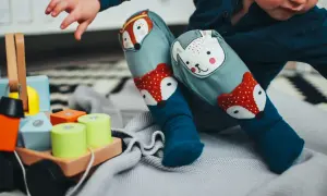 Dziecko w kolorowych skarpetkach z liskiem i misiem bawi się klockami. Wesołe zabawy dla dzieci w żłobku.