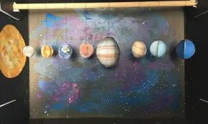 Model układu słonecznego, pokazujący, jak zrobić planety z papieru. Słońce i osiem wiszących planet na tle kosmicznej mgławicy.