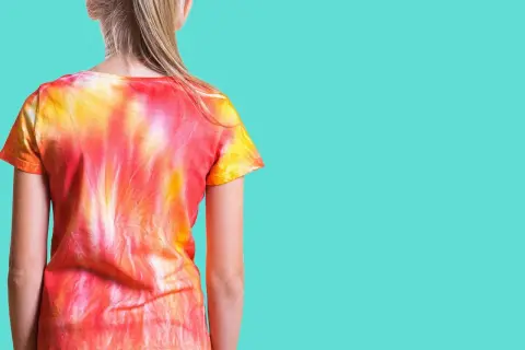 Dziewczynka w koszulce tie dye w odcieniach czerwieni i żółci. Zobacz, jak zrobić tie dye krok po kroku!
