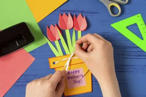 Ręcznie robiony prezent dla mamy od dziecka: żółta doniczka z papierowymi tulipanami i karteczką "Happy Mother's Day".