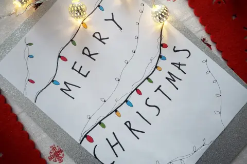 Świąteczne rysunki ołówkiem z kolorowymi lampkami tworzą napis "Merry Christmas".