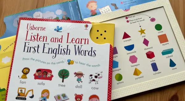 Interaktywne materiały do nauki angielskiego dla dzieci: książka "Listen and Learn First English Words" z obrazkami zwierząt, przedmiotów i kształtów.