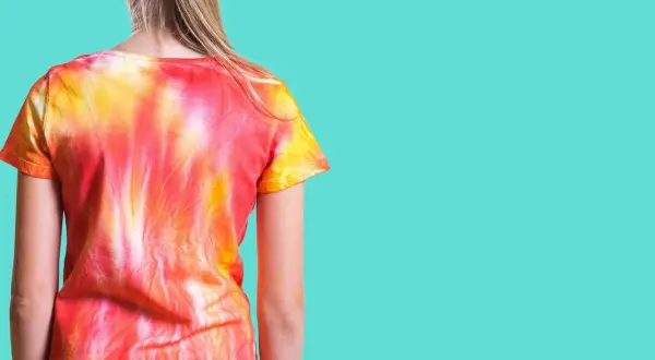 Dziewczynka w koszulce tie dye w odcieniach czerwieni i żółci. Zobacz, jak zrobić tie dye krok po kroku!