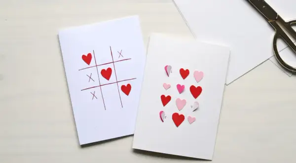 Dwie kartki walentynkowe: jedna z grą w kółko i krzyżyk z serduszkami, druga z serduszkami i literami tworzącymi słowo "LOVE".