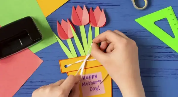 Ręcznie robiony prezent dla mamy od dziecka: żółta doniczka z papierowymi tulipanami i karteczką "Happy Mother's Day".