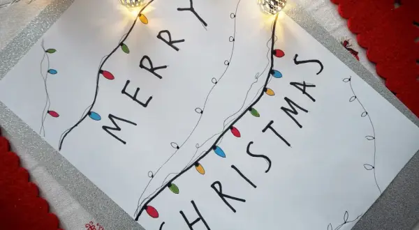 Świąteczne rysunki ołówkiem z kolorowymi lampkami tworzą napis "Merry Christmas".