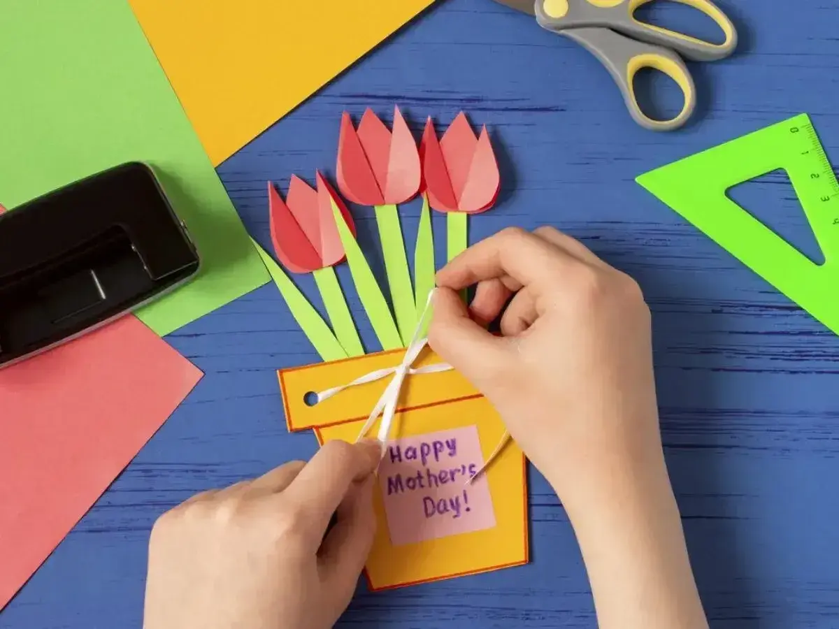 Ręcznie robiony prezent dla mamy od dziecka: żółta doniczka z papierowymi tulipanami i karteczką "Happy Mother's Day".