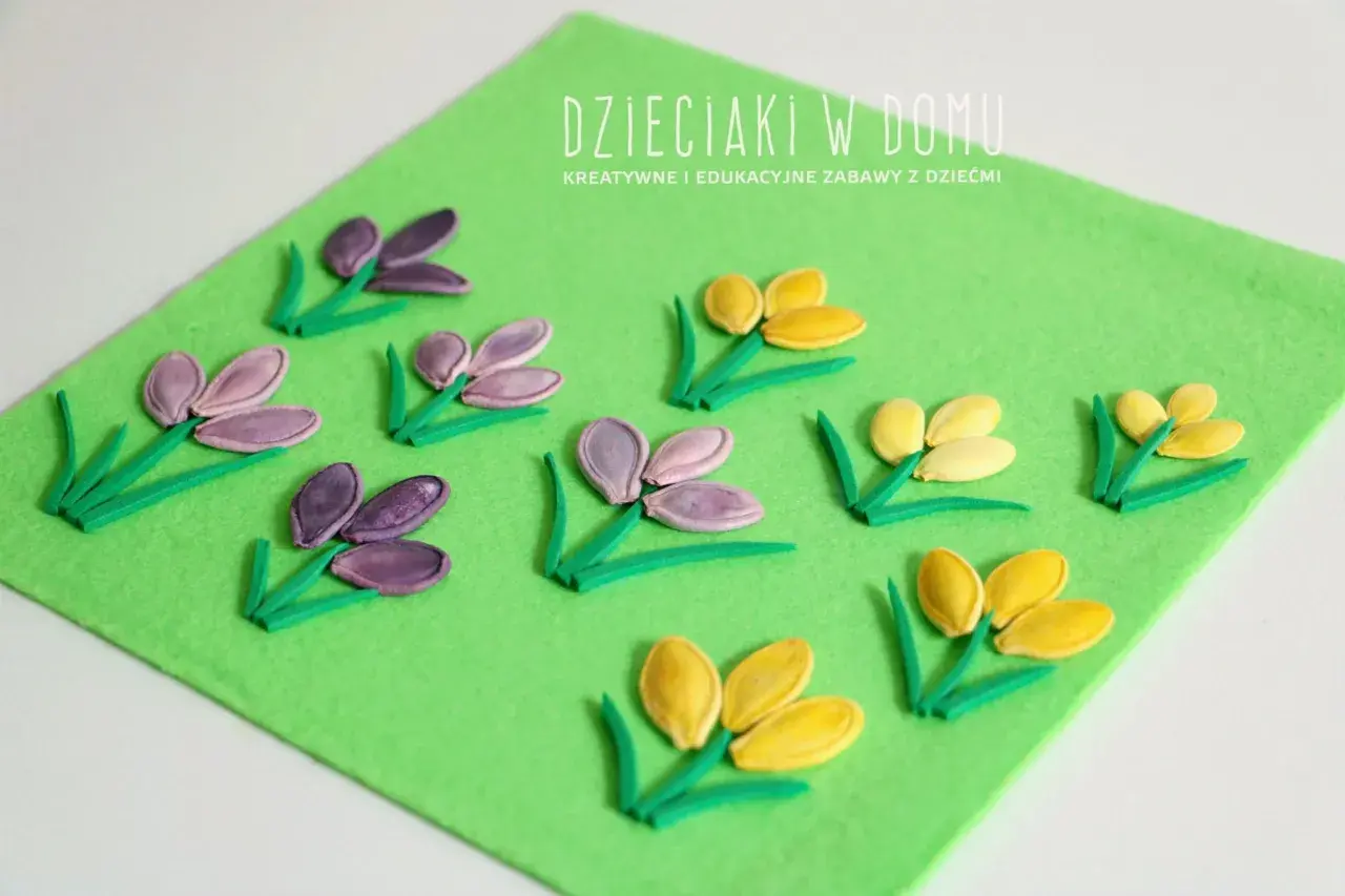 Wiosenne kwiaty z pestek dyni na zielonym filcu. Dzieciaki w domu tworzą piękne, kolorowe kompozycje.