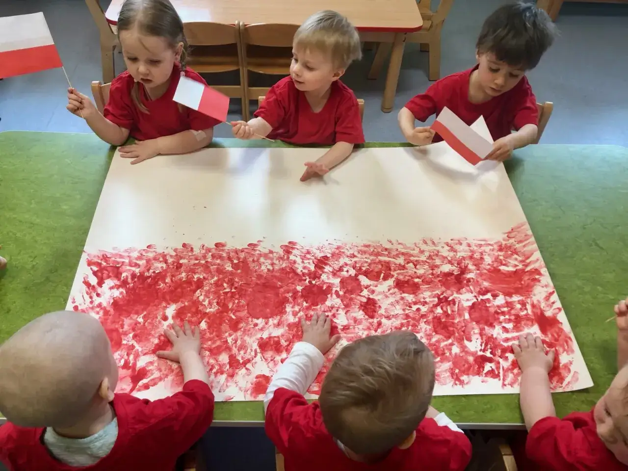 Dzieci tworzą pracę plastyczną na Dzień Flagi, malując biało-czerwone wzory.