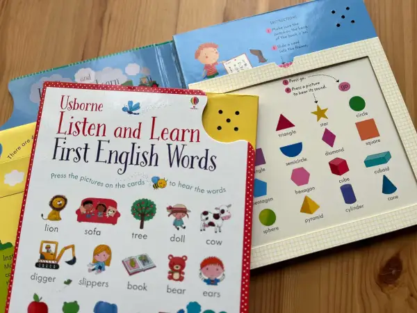 Interaktywne materiały do nauki angielskiego dla dzieci: książka "Listen and Learn First English Words" z obrazkami zwierząt, przedmiotów i kształtów.