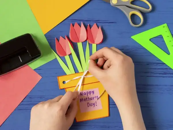 Ręcznie robiony prezent dla mamy od dziecka: żółta doniczka z papierowymi tulipanami i karteczką "Happy Mother's Day".