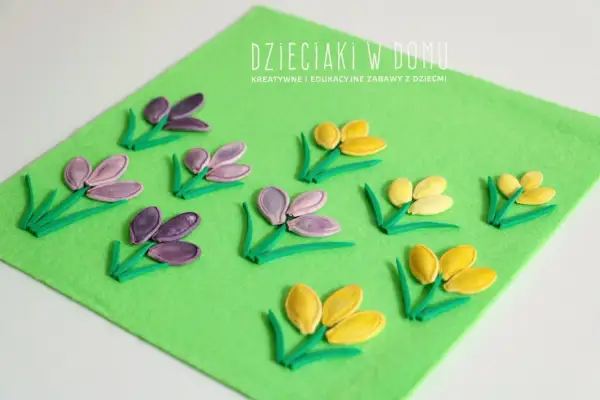 Wiosenne kwiaty z pestek dyni na zielonym filcu. Dzieciaki w domu tworzą piękne, kolorowe kompozycje.